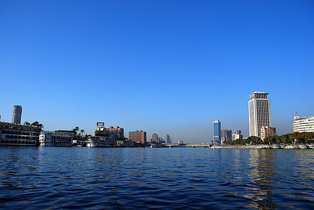 photography of body of water near concrete buildings at daytime thumbnail