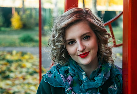 Woman Wearing Blue and Purple Floral Print Scarf Taking a Selfie thumbnail