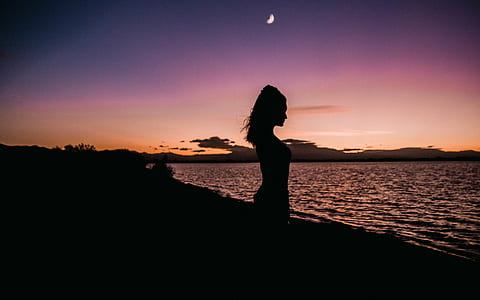 silhouette of woman on seashore at golden hour thumbnail