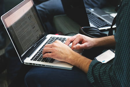 person wearing black and green checked shirt using MacBook Pro thumbnail