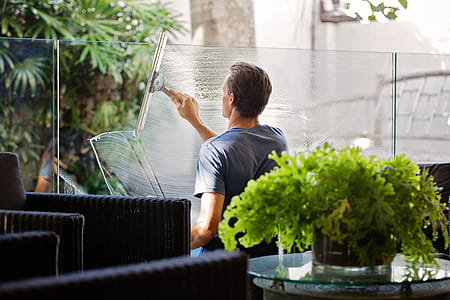 Man in Gray Shirt Cleaning Clear Glass Wall Near Sofa thumbnail