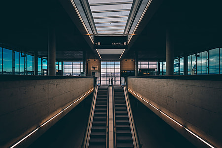 black and gray escalator surrounded by concrete wall thumbnail