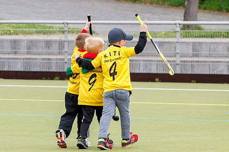 three boy wearing yellow jersey holding a field hockey sticks thumbnail
