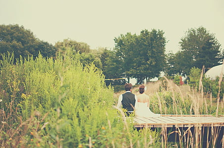 married couple sitting on brown dock thumbnail