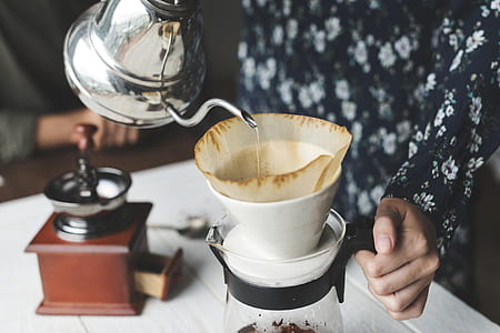 person holding teapot while pouring liquid in cup thumbnail
