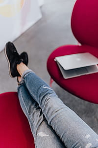 Woman using laptop computer and sitting cross legs on sofa thumbnail