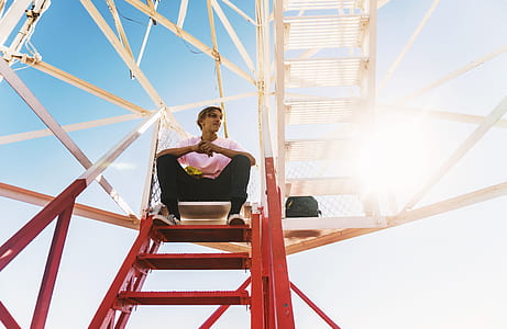 man sitting on red metal staircase thumbnail
