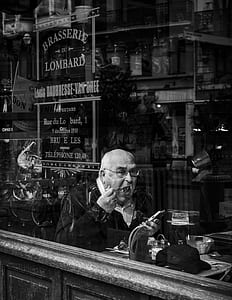 grayscale photography of man eating inside cafeteria thumbnail