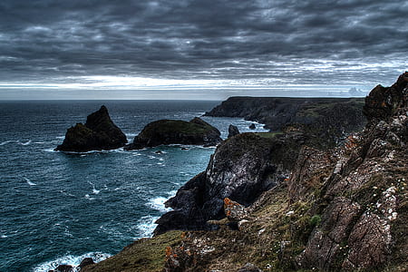rock formations on body of water under cloudy sky thumbnail