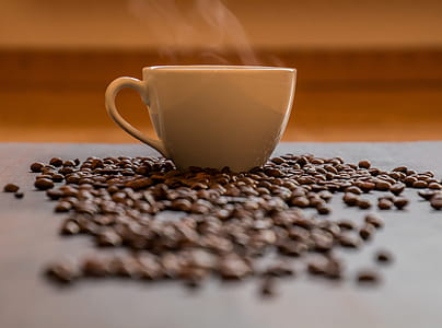 White Ceramic Teacup With Smokes Surrounded by Coffee Beans in Selective Focus Photography thumbnail