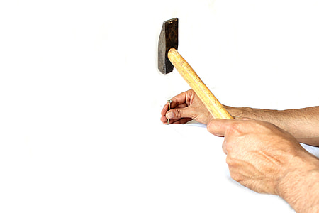 person's hand holding common nail and hammer thumbnail