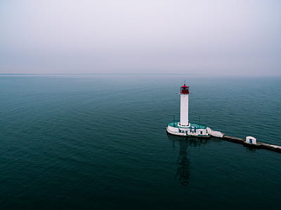 white and teal lighthouse surrounded by ocean thumbnail