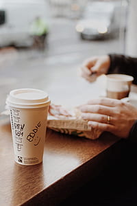 white disposable cup near person's hand selective focus photography thumbnail