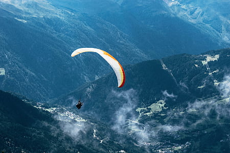 person parachuting above green mountain during daytime thumbnail