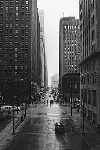 grayscale photo of vehicles on road near buildings thumbnail