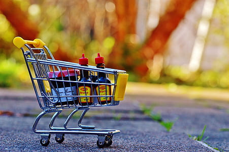gray metal shoppers cart on gray pavement in tilt-shift photo thumbnail