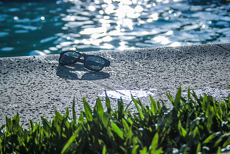 black sunglasses beside swimming pool thumbnail