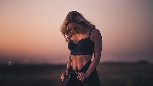 woman wearing black crop top holding strings to pants looking down thumbnail