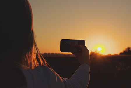 Silhouette Photo of Woman Taking Photo of Sunset thumbnail