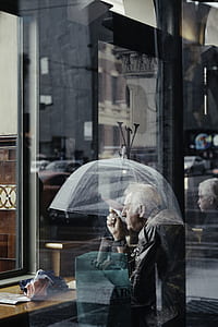 man carrying umbrella near glass panel during daytime thumbnail