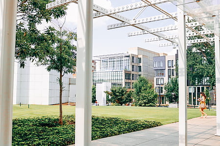 woman walking beside white building under blue sky thumbnail