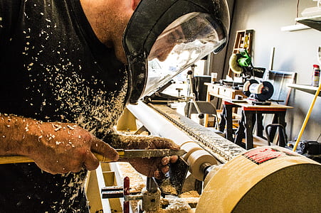 man wearing helmet carving wood thumbnail
