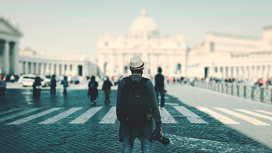 man in grey jacket standing while holding black DSLR camera on road during daytime thumbnail