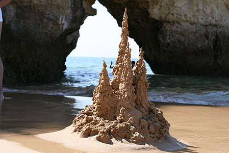 brown sandcastle near body of water thumbnail