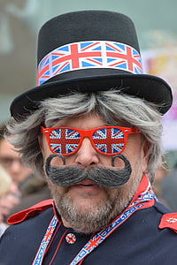 man wearing UK flag top hat with sunglasses outdoors thumbnail