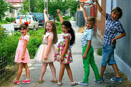 five children raising right arms beside green bush thumbnail