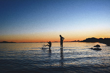 silhouette of two person's on body of water during sunset thumbnail