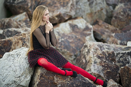 woman in black dress and red leggings with black heels sitting on rack during daytime thumbnail