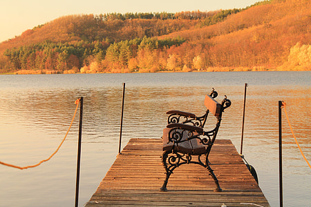 brown and black outdoor bench near the end of wooden dock on body of water thumbnail