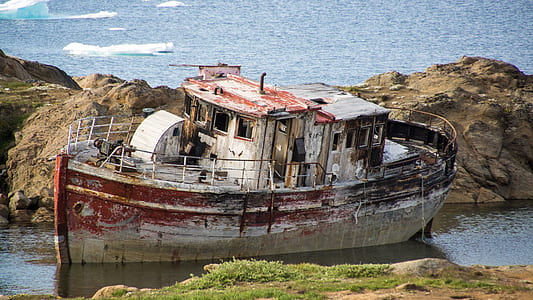 wrecked ship on shore near rock cliff thumbnail