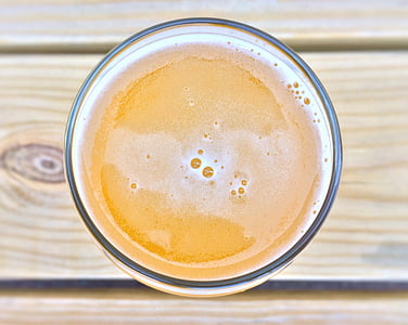 closeup of foamy liquid clear drinking glass on wooden surface thumbnail
