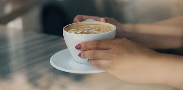 person holding cup of coffee on saucer thumbnail