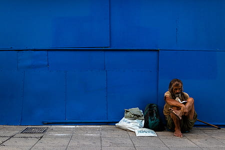 man sitting on road near wall thumbnail