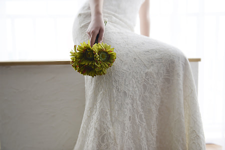 woman wearing white gown and holding green flowers thumbnail