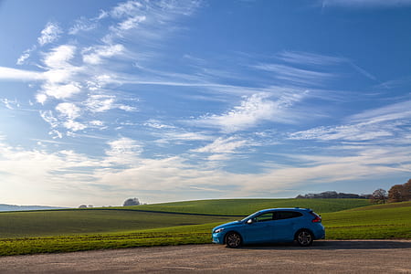 blue hatchback parked near green grass field thumbnail
