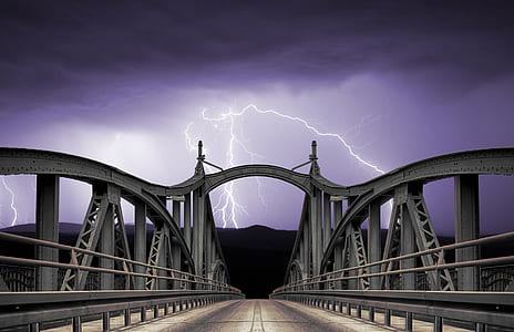 grey metal suspension bridge under cloudy skies with lightnings thumbnail