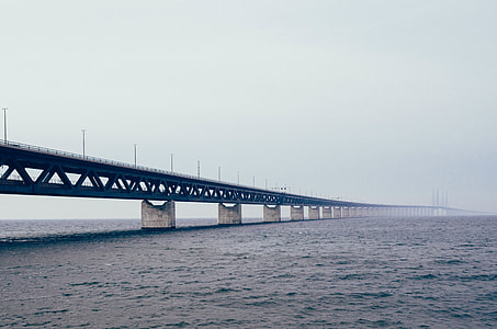 bridge under clear sky above large body of water thumbnail