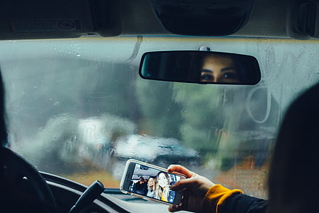 person holding white smartphone in clear case taking selfie white sitting inside the vehicle thumbnail