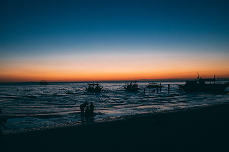 silhouette photography of people standing on seashore thumbnail