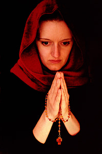 woman praying while holding prayer beads thumbnail
