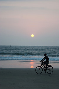 silhouette of man riding on bicycle near wide ocean during sunset thumbnail
