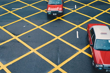 two red Hong Kong Taxi cabs on parking lot during daytime thumbnail