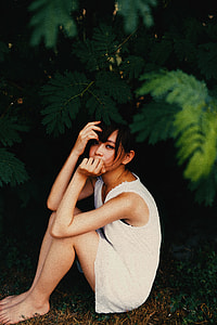 girl sitting on grass while holding her mouth and hair thumbnail