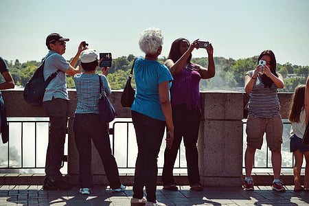 people holding smartphones and camera near bridge thumbnail