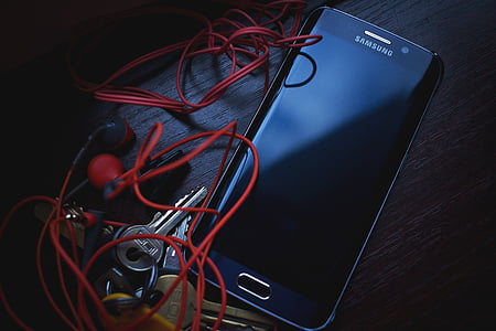 blue Samsung Android smartphone beside red earbuds and keys thumbnail