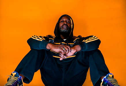 sitting man in black and yellow adidas hooded jacket and pants thumbnail